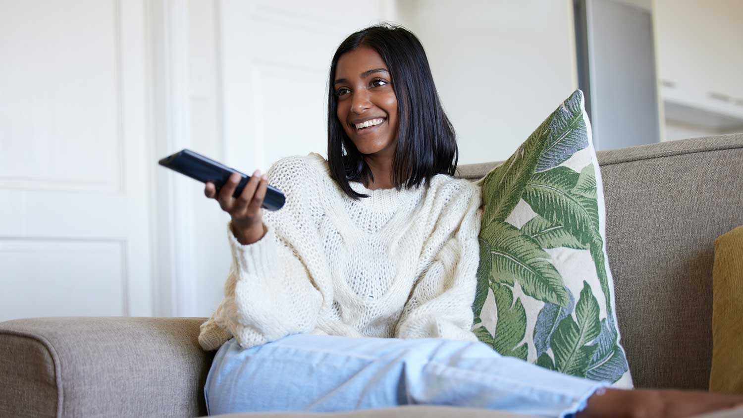 Woman sitting on the couch holding a tv remote control