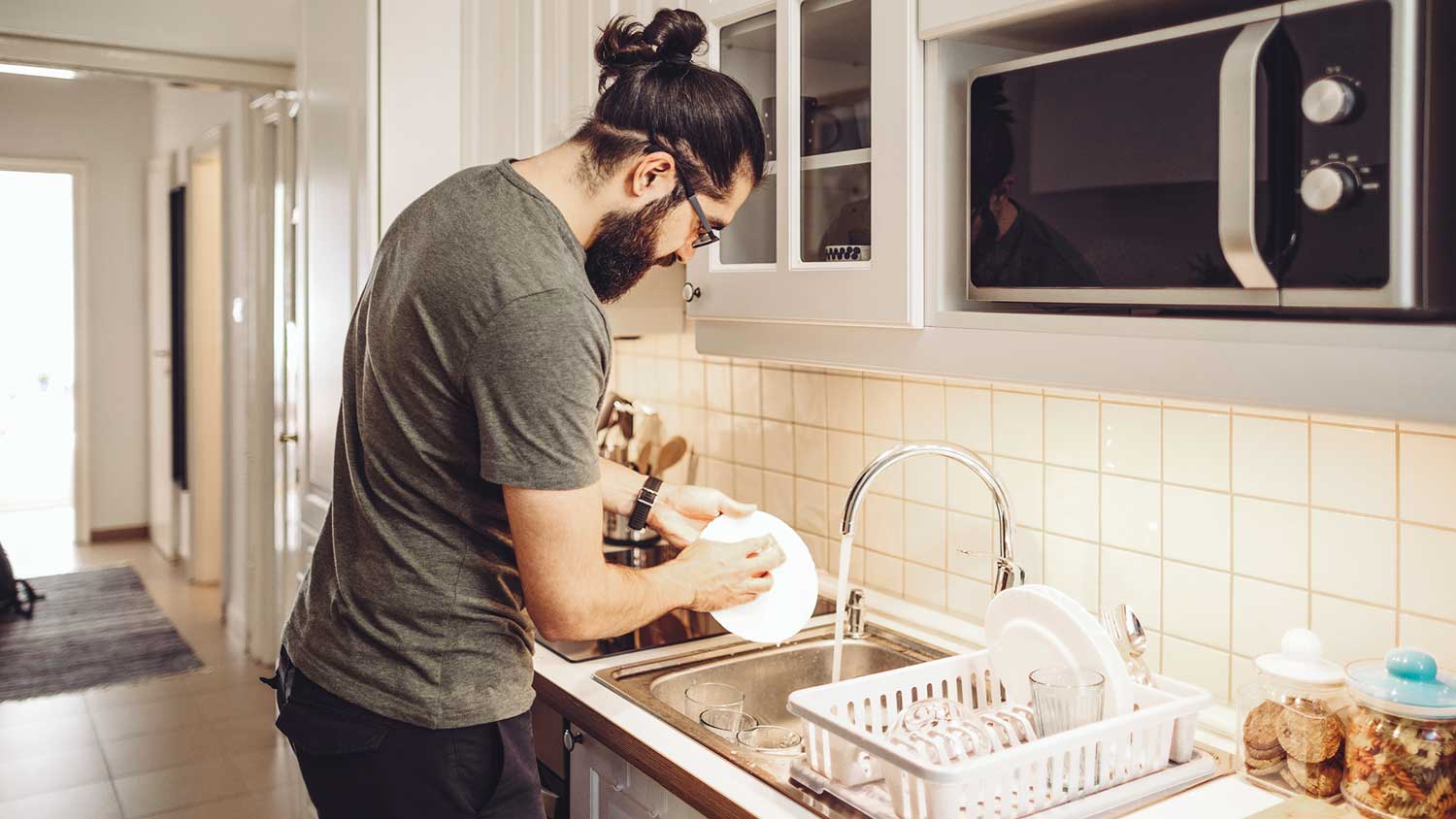 Young man washing dishes in the kitchen sink