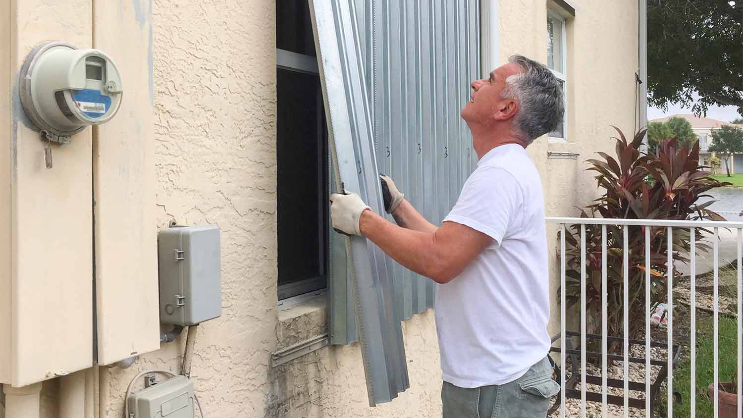 man installing hurricane shutters