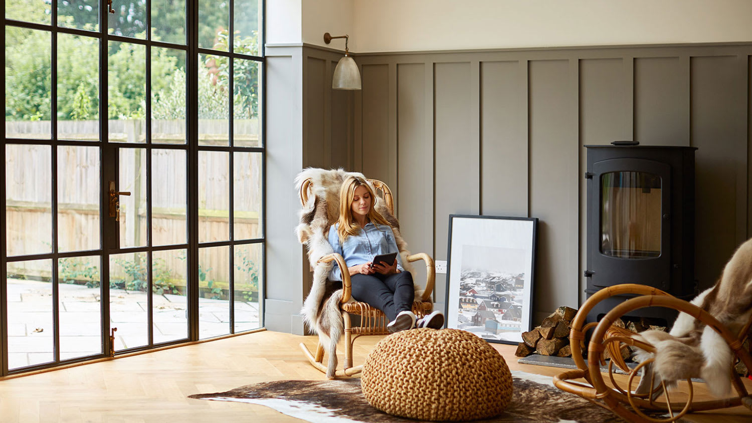 woman sitting in a rocking chair in a cozy room by large glass window