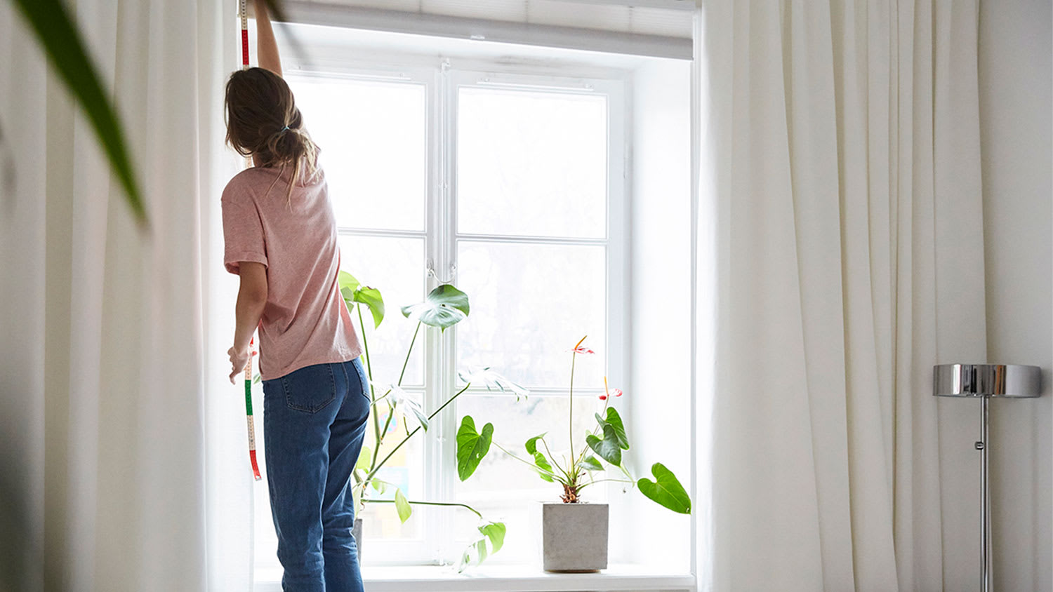 A woman installs curtains