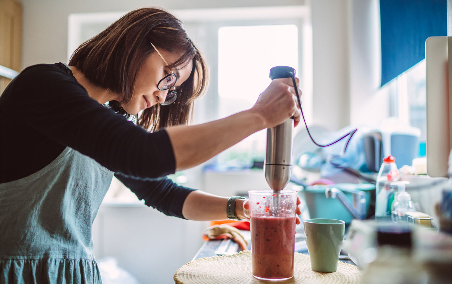 woman making a smoothie with an electric blende