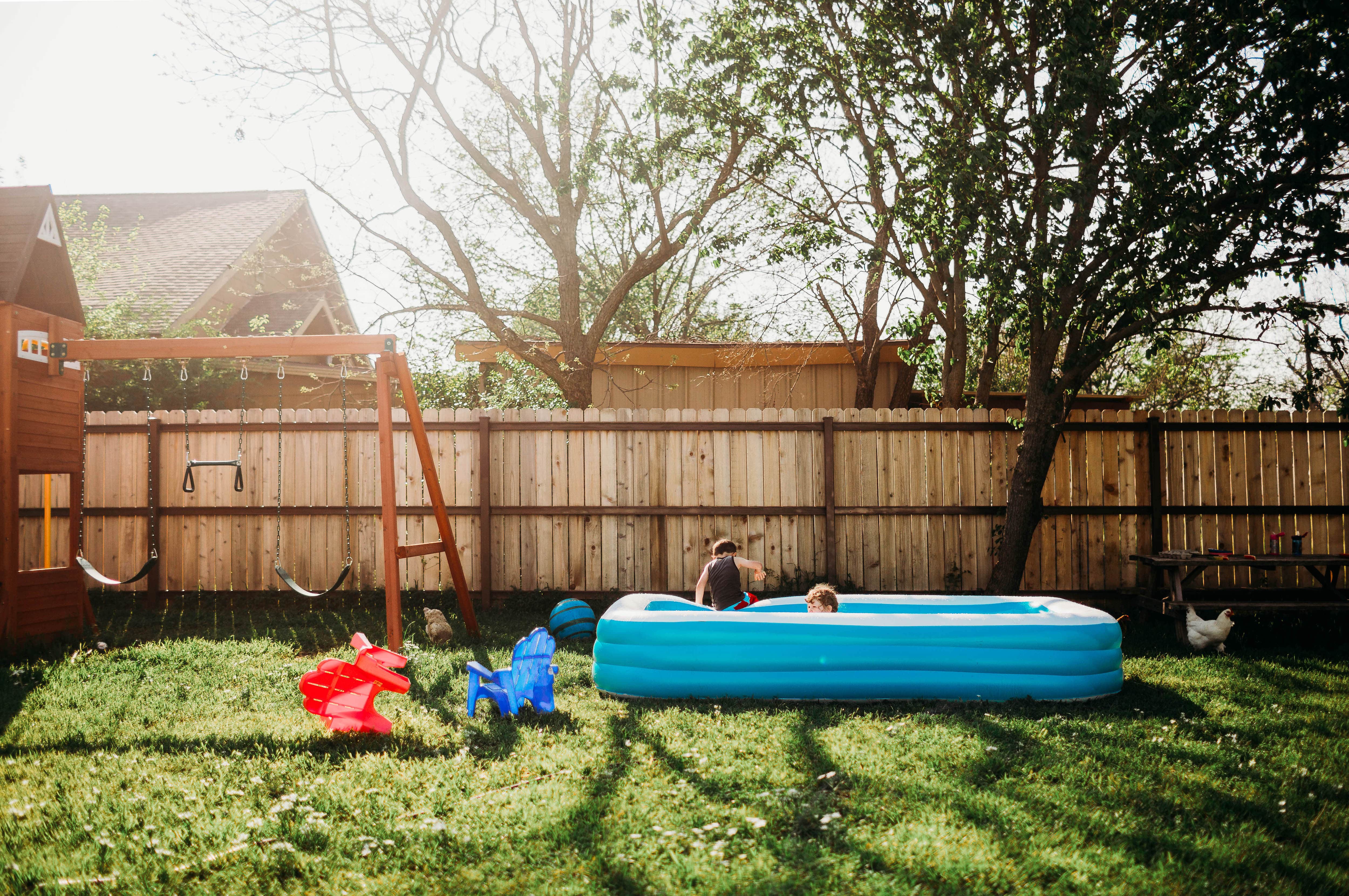 Kids playing in pool in yard with wood fence enclosure