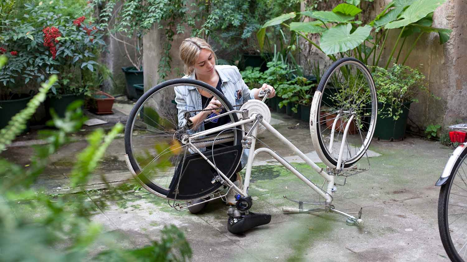 Young woman in a courtyard fixing her bicycle