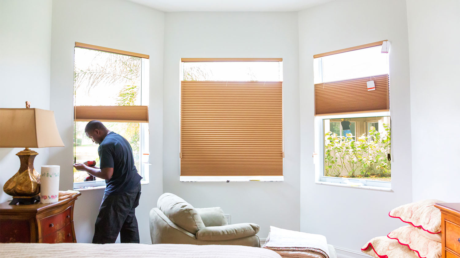 A man installs window blinds