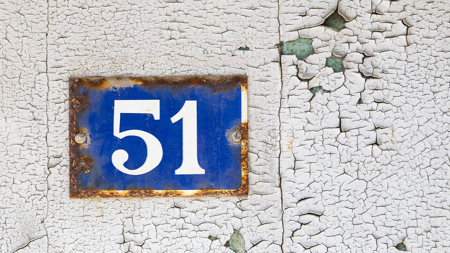 rusty blue metal sign with house number 51