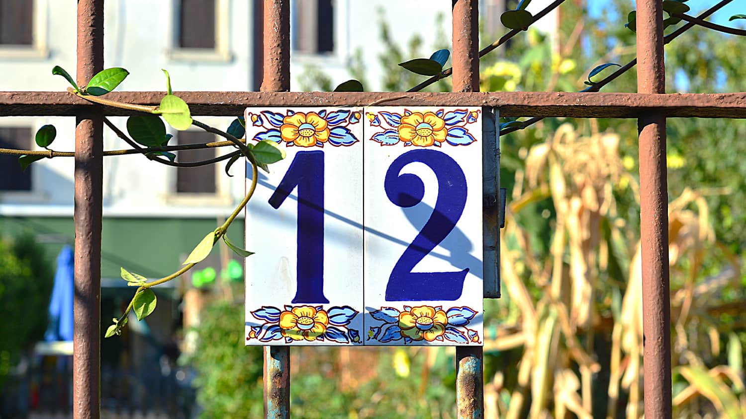 closeup of fence in front yard with tile house numbers hanging on fence (#12)