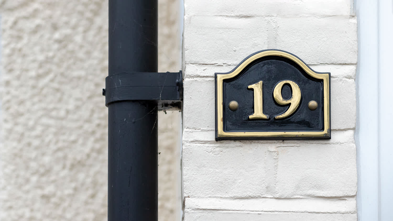 brass #19 house number sign on white brick