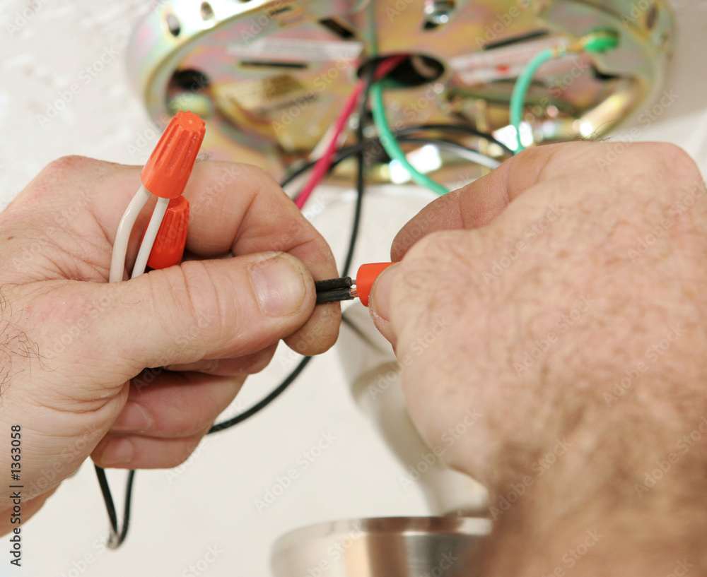 Close-up of a person wiring a ceiling fan