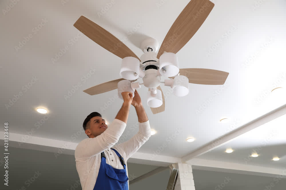 An electrician installing a new ceiling fan