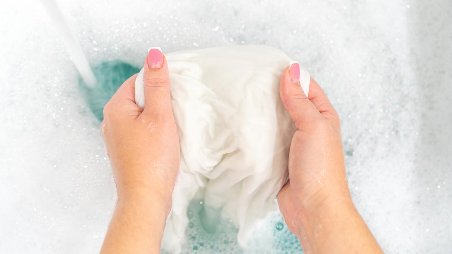 A woman washing clothes by hand with bleach