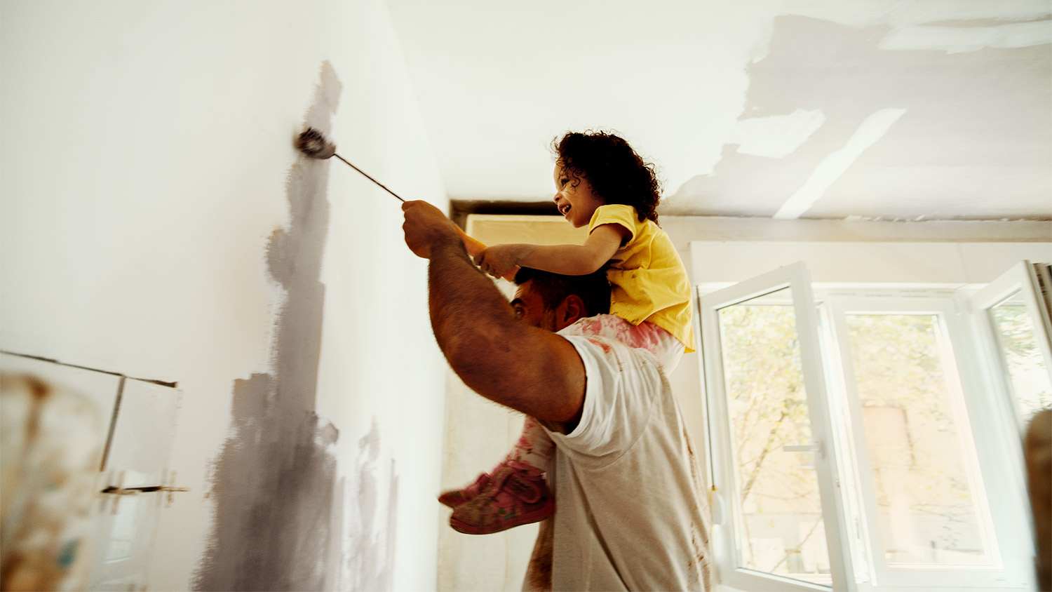 Father and daughter renovating painting a wall in their home