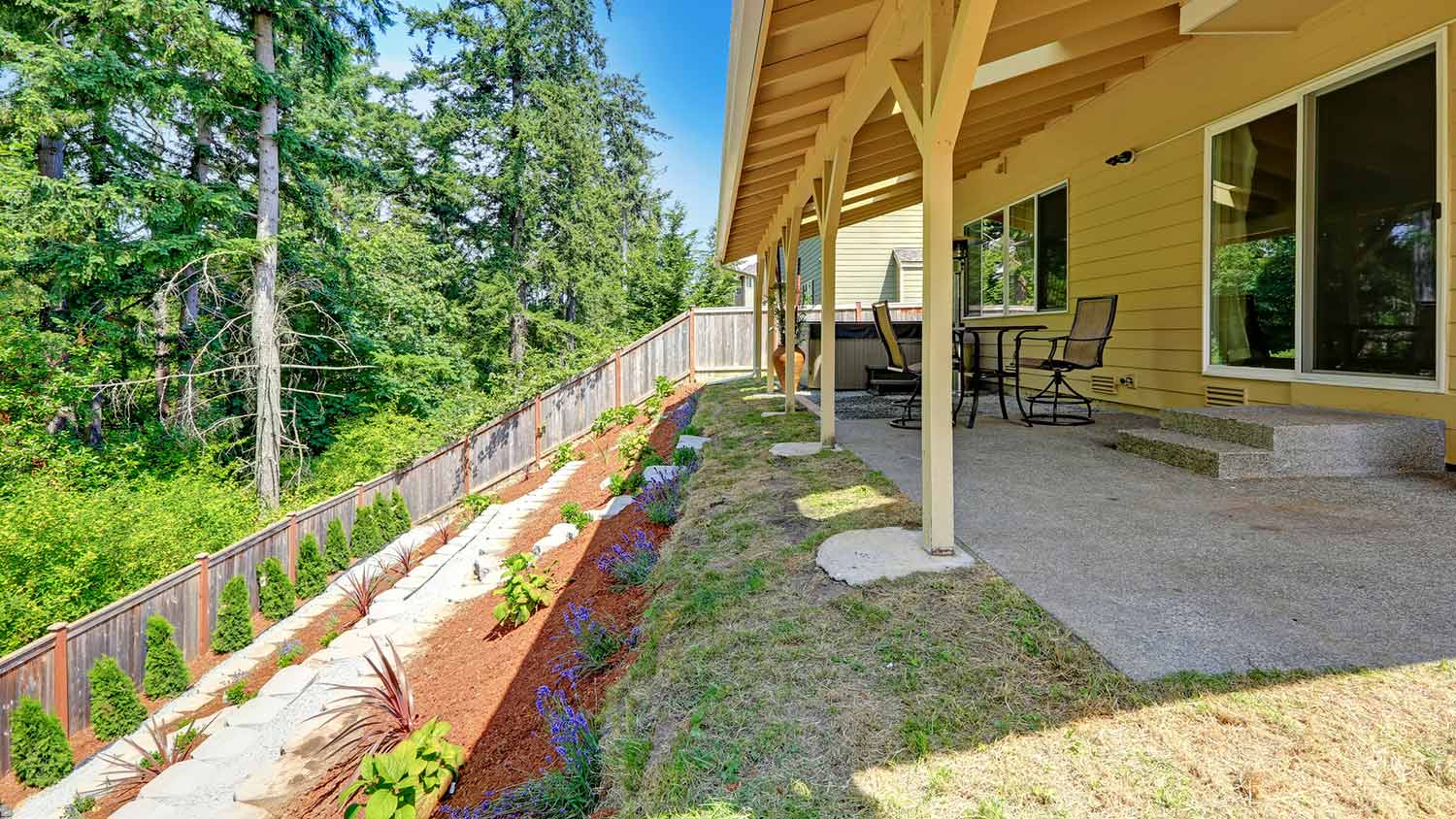 Sloping back yard with fence cutting off woods