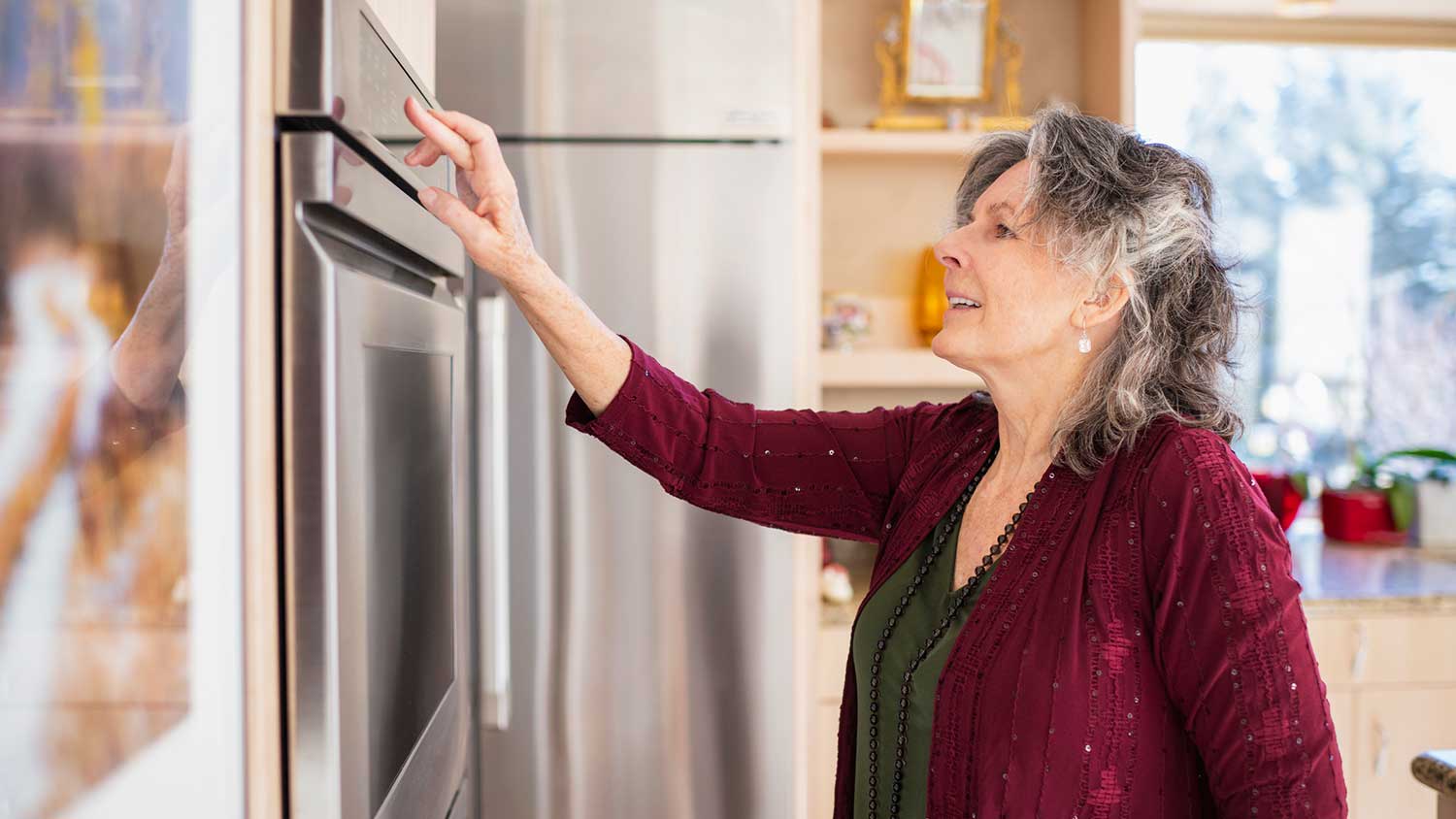 Woman in her kitchen adjusting oven settings