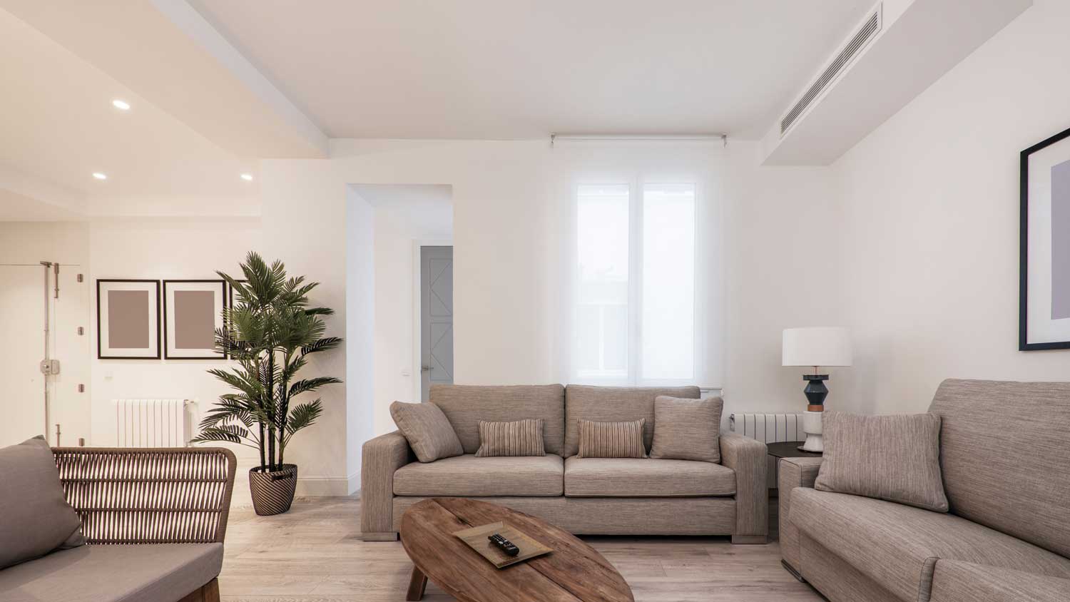 A spacious living room with an air duct above the sofa