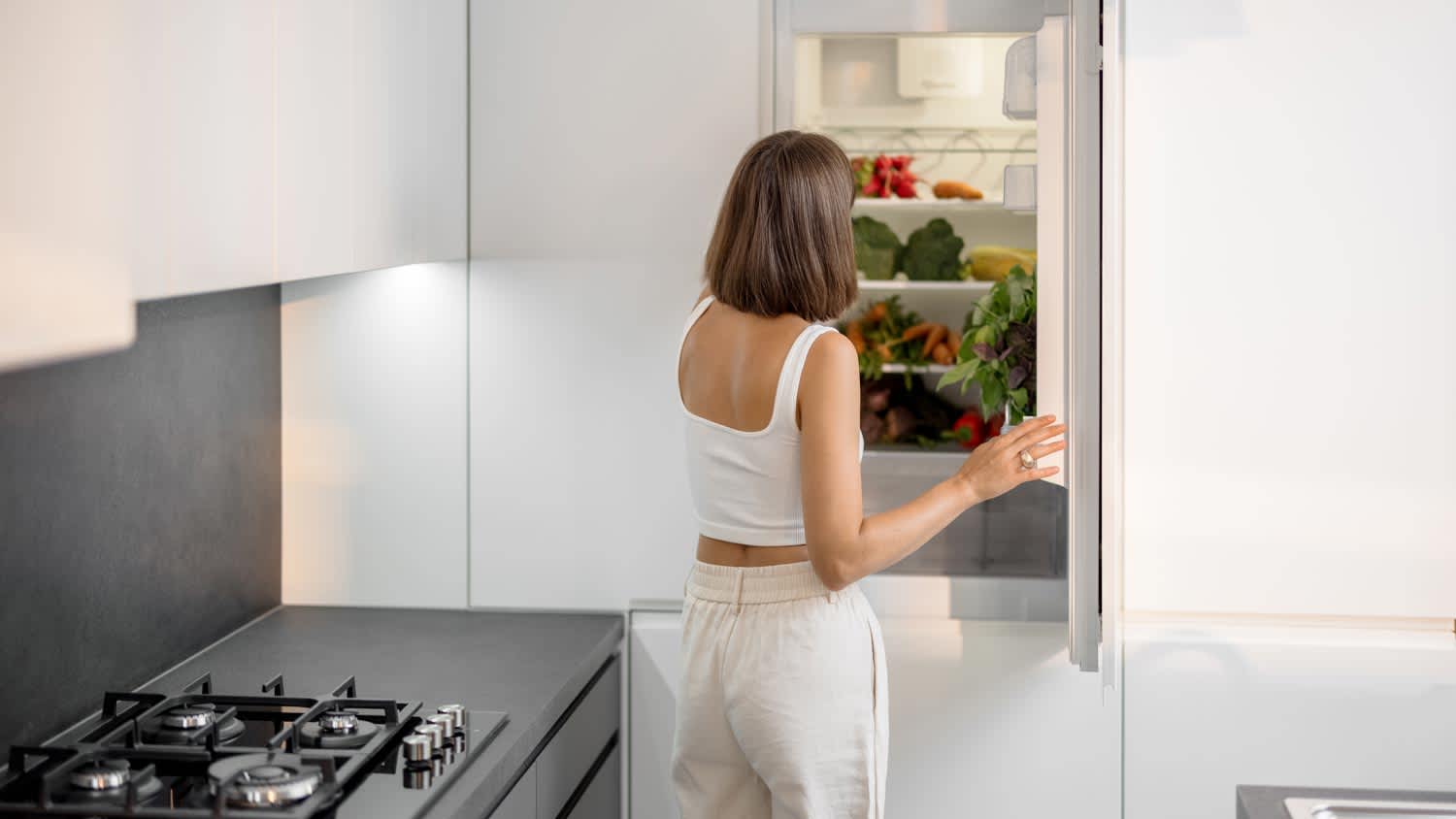 A woman in front of an open fridge in a modern kitchen