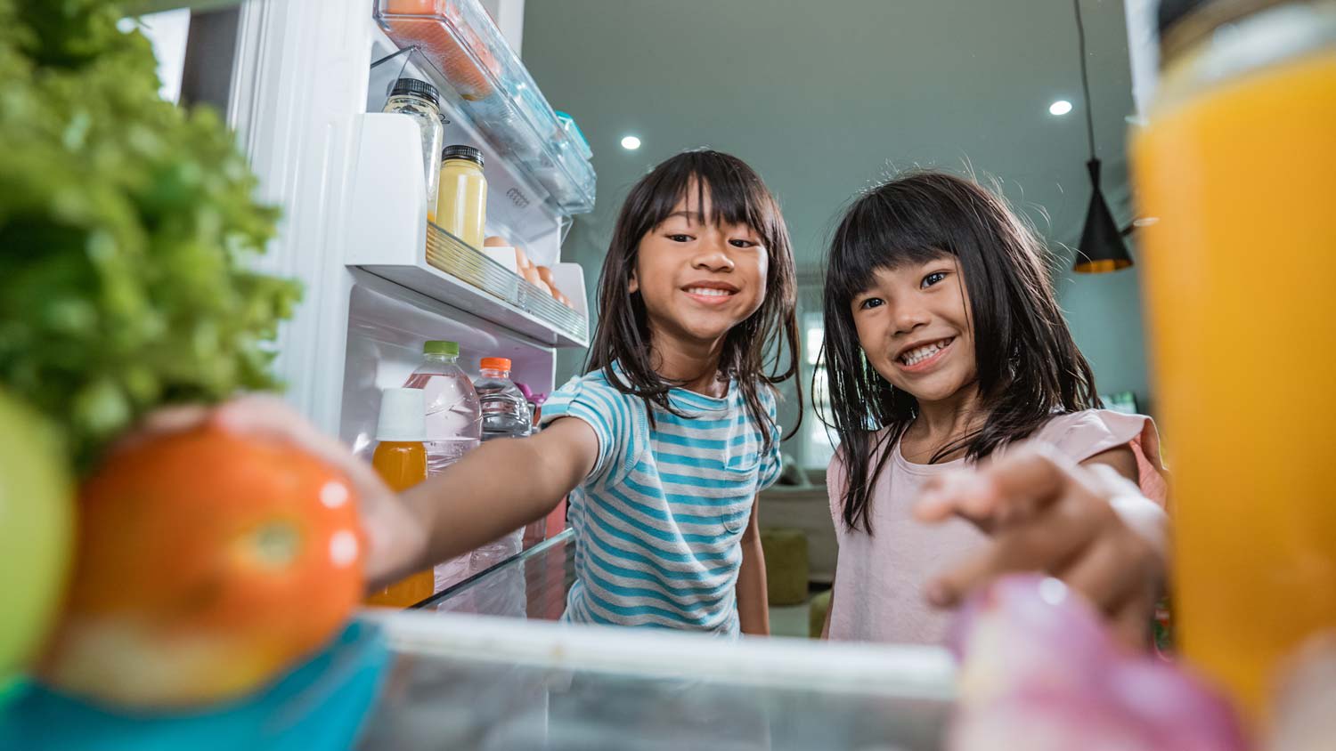 Two kids checking inside the refrigerator