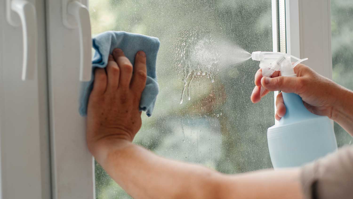 A man spraying window with cleaner