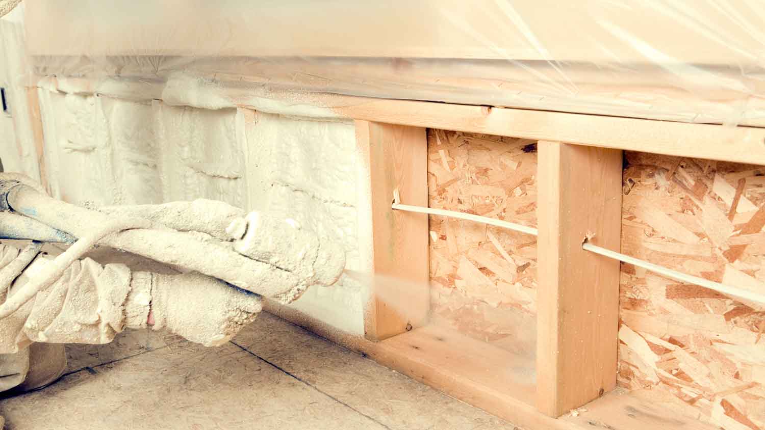 Worker spraying foam insulation in a new construction