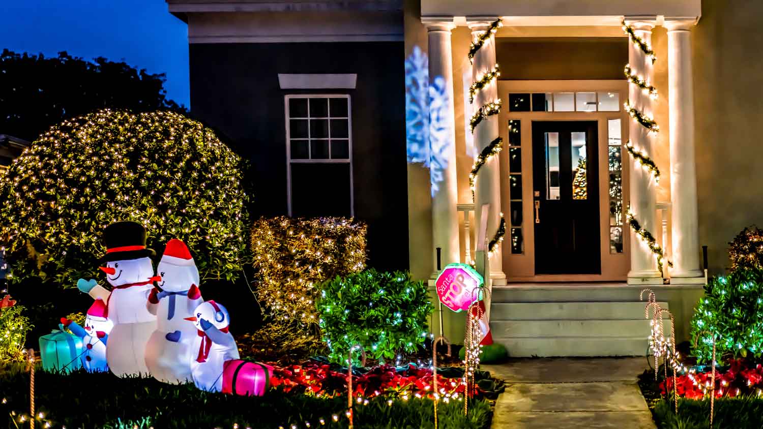 Christmas lights on bushes and the pillars of a house
