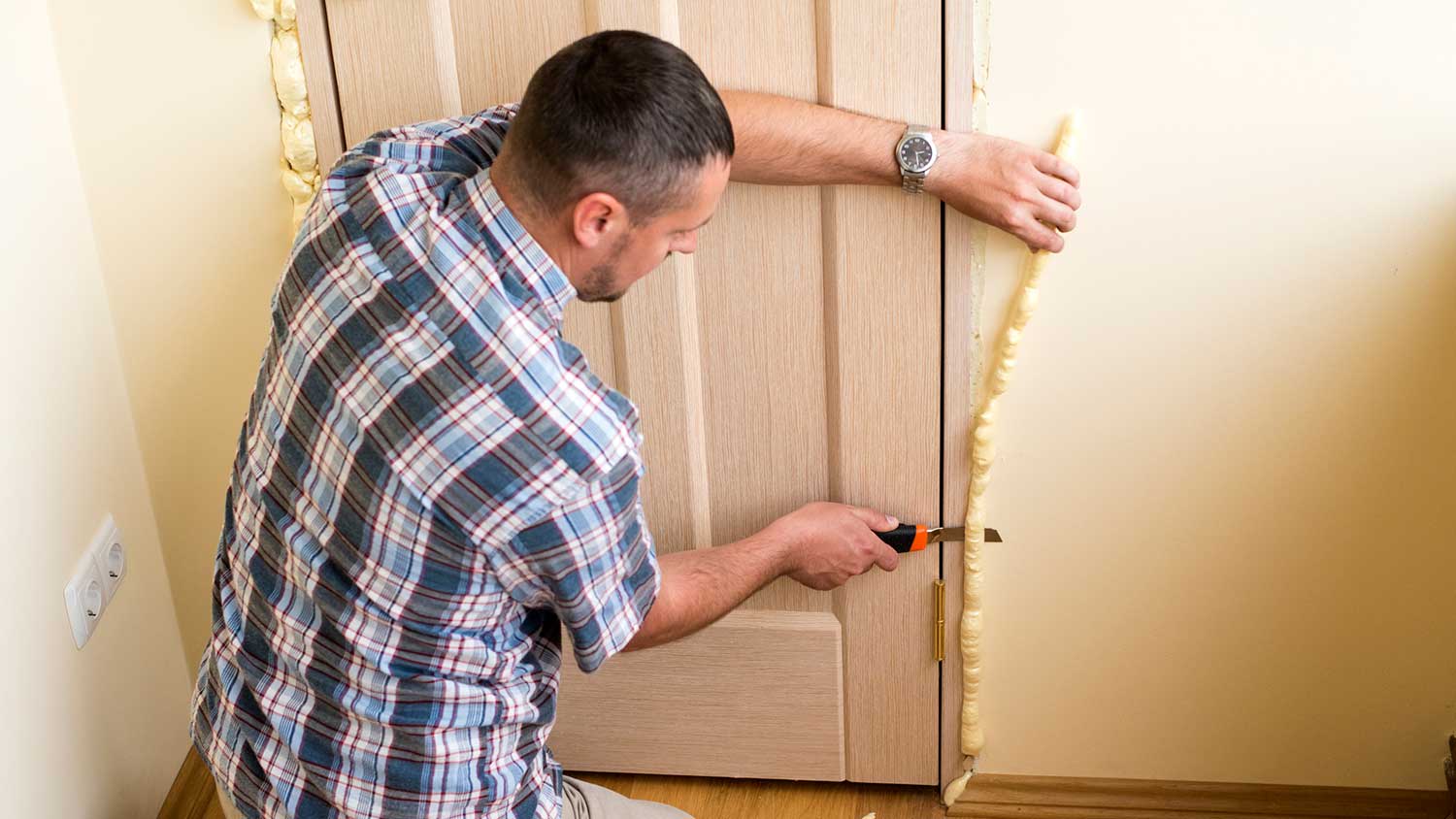 Handyman installing polyurethane foam insulation around the door
