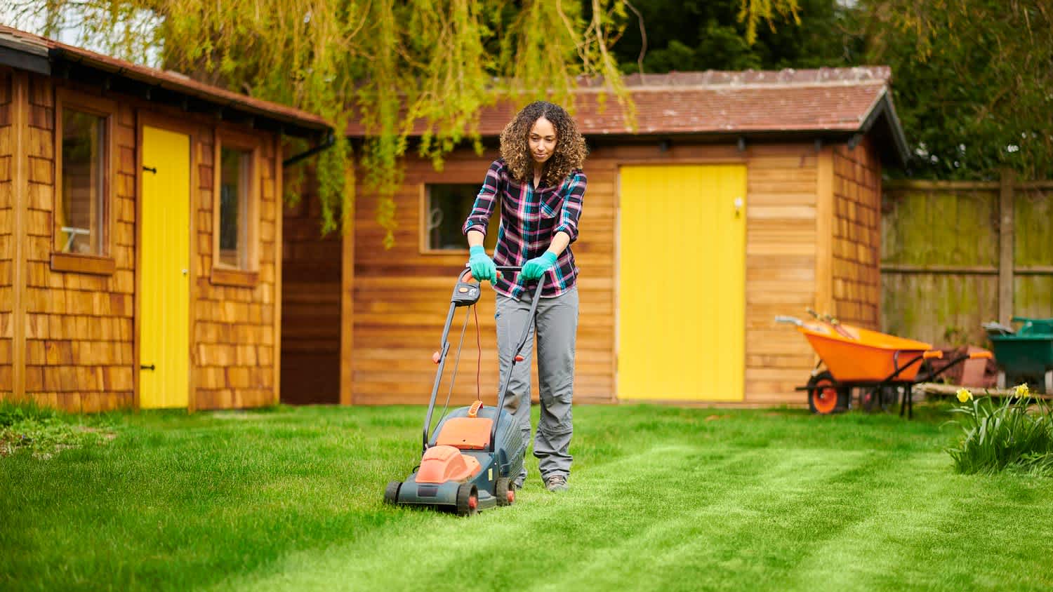 A woman mowing the lawn in the backyard