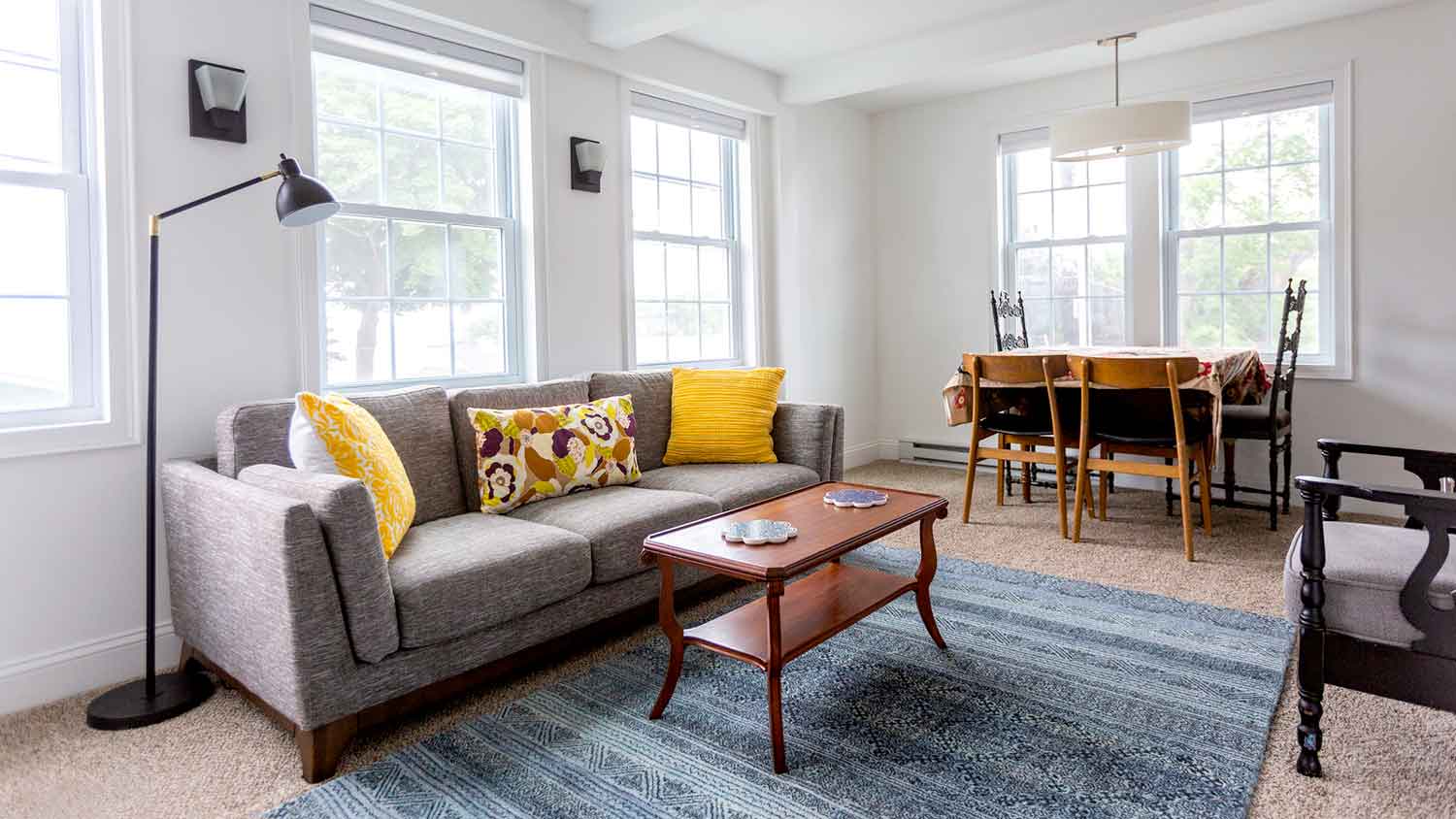 Bright living room with gray sofa and dining table