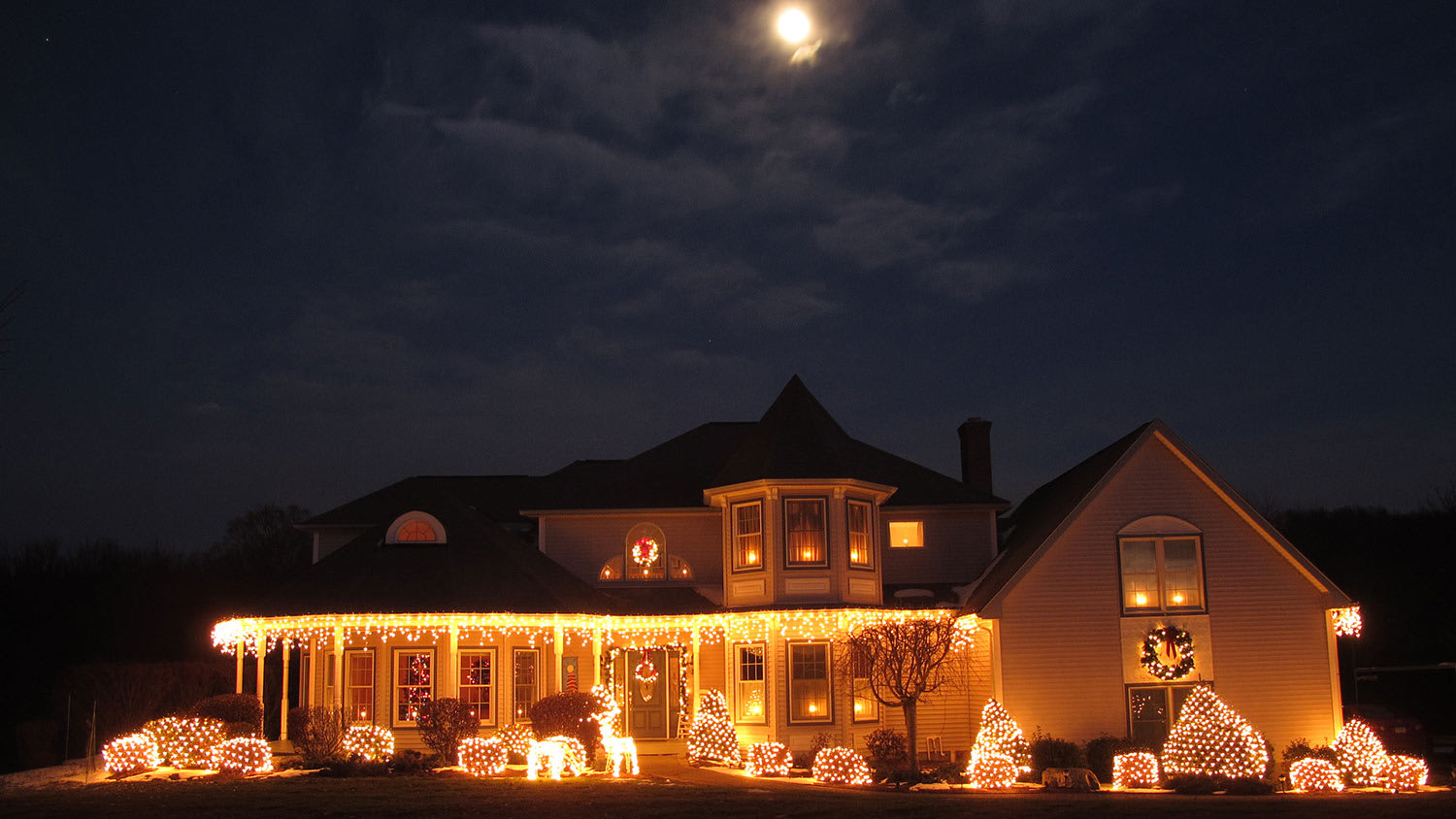 House lit up with Christmas lights under the moon