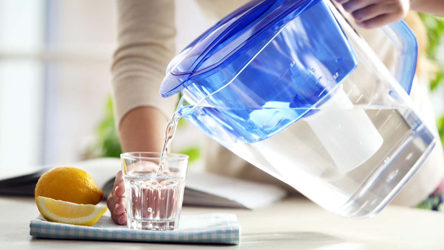 A woman pouring water in a glass from a water filter pitcher