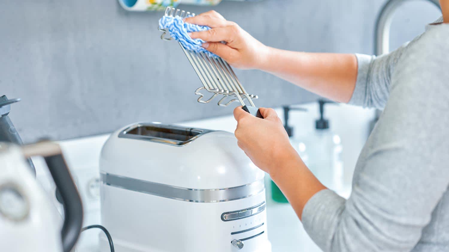 A woman cleaning the toaster’s grill