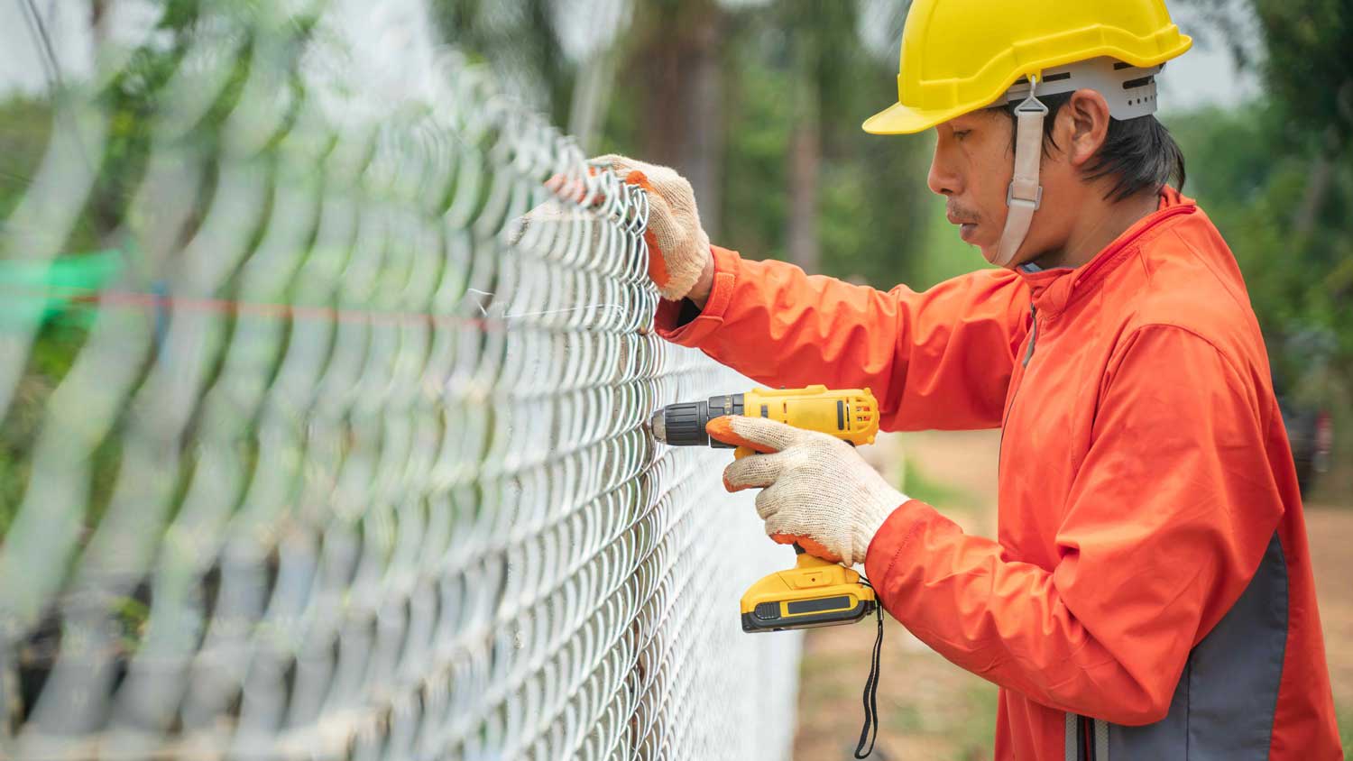 A worker removing a chain link fence