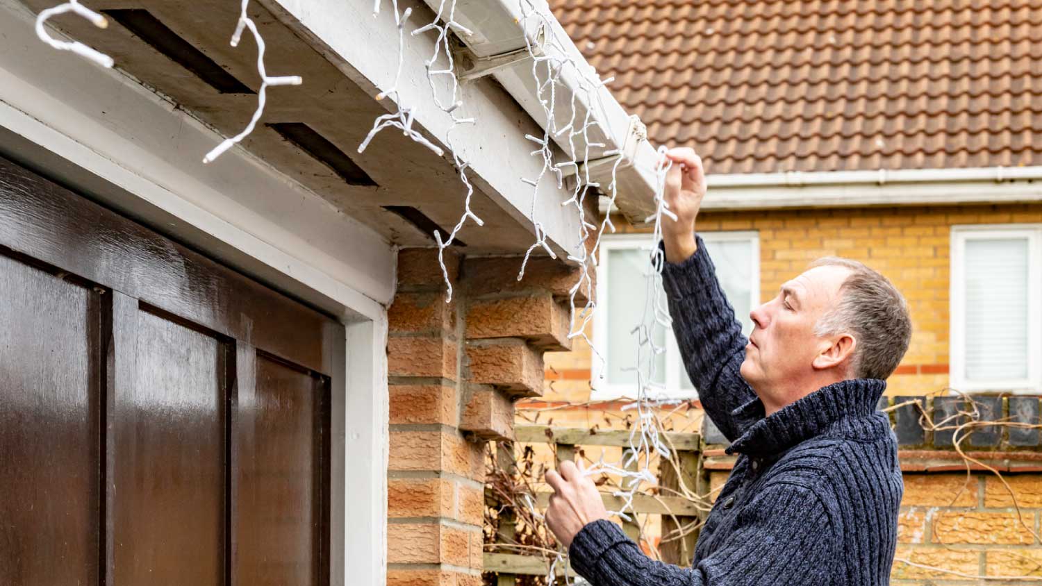 Man taking down outdoor Christmas lights