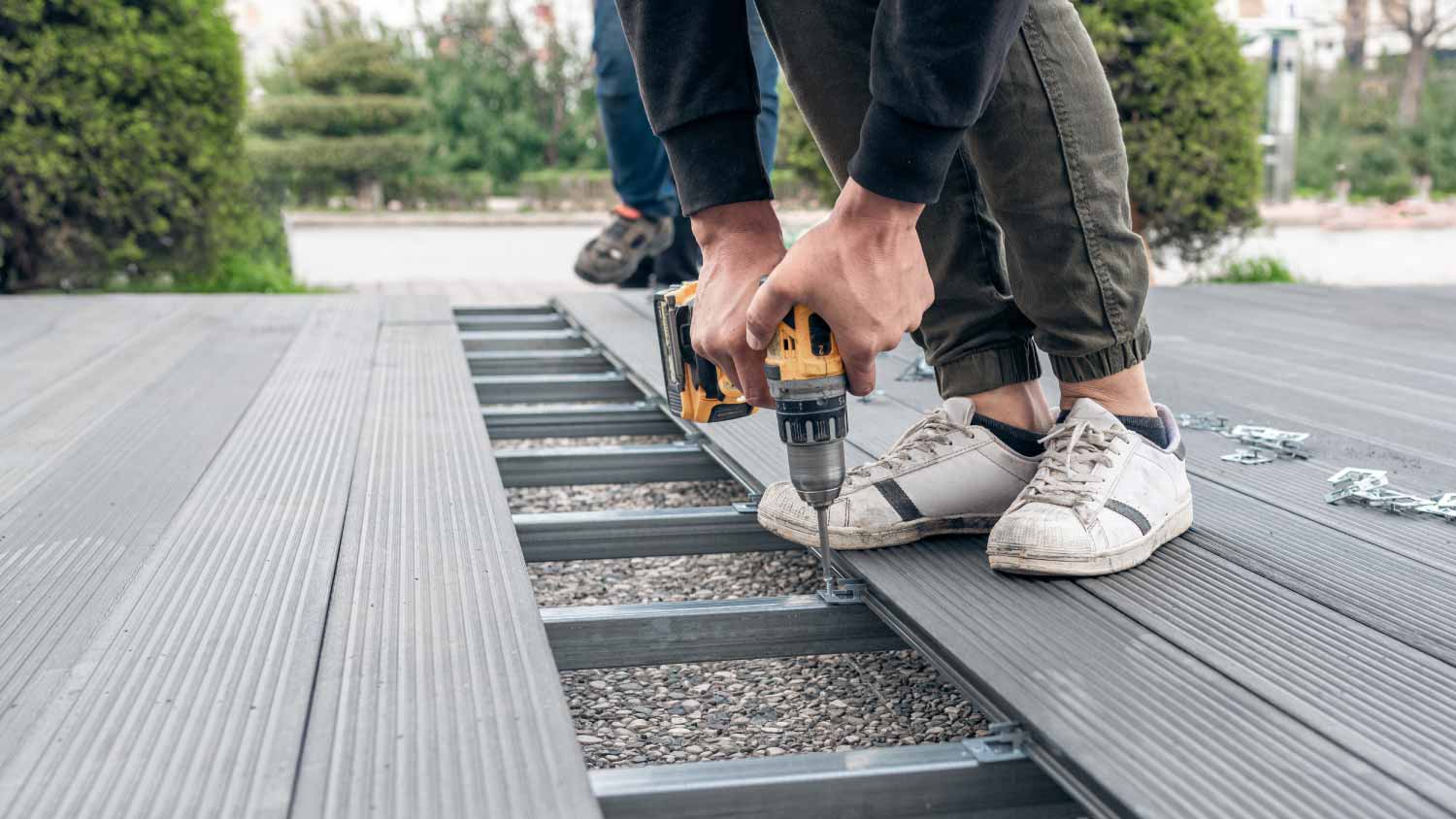 Man assembling composite deck using cordless screwdriver