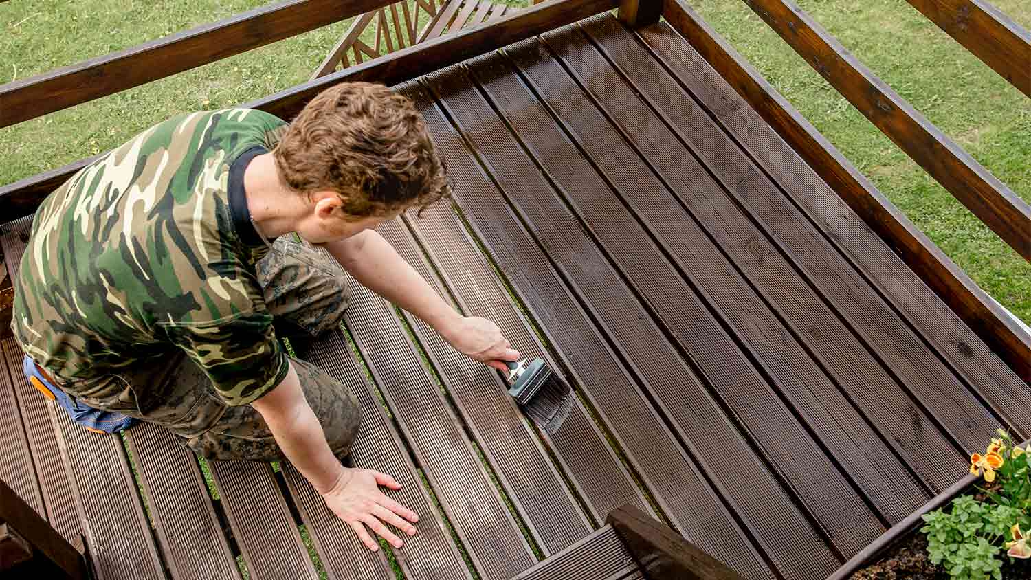 A man stains a wood deck