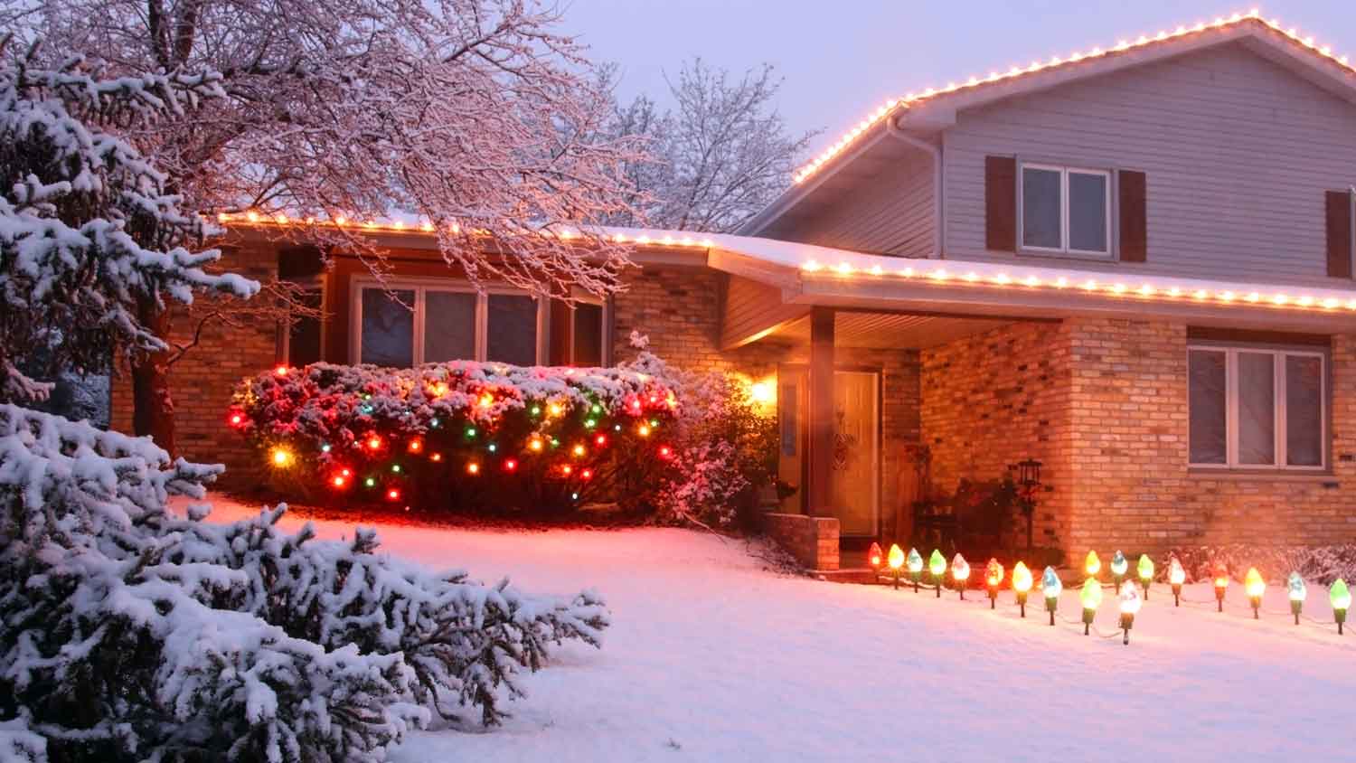 A beautiful snow covered house with various Christmas lights