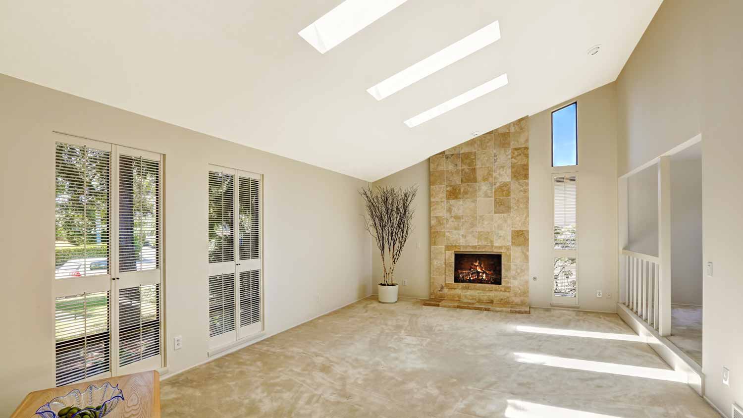 Vaulted ceiling with skylights in an empty space with a fireplace