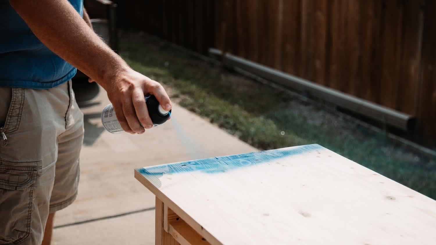 A man spray painting a wooden furniture