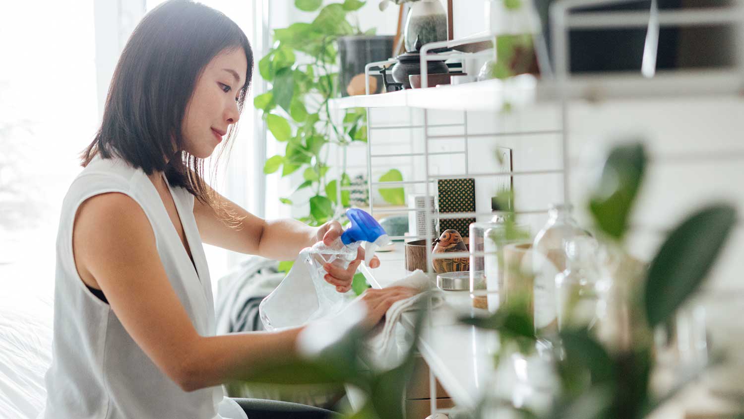 Woman at home cleaning shelves with cleaning spray