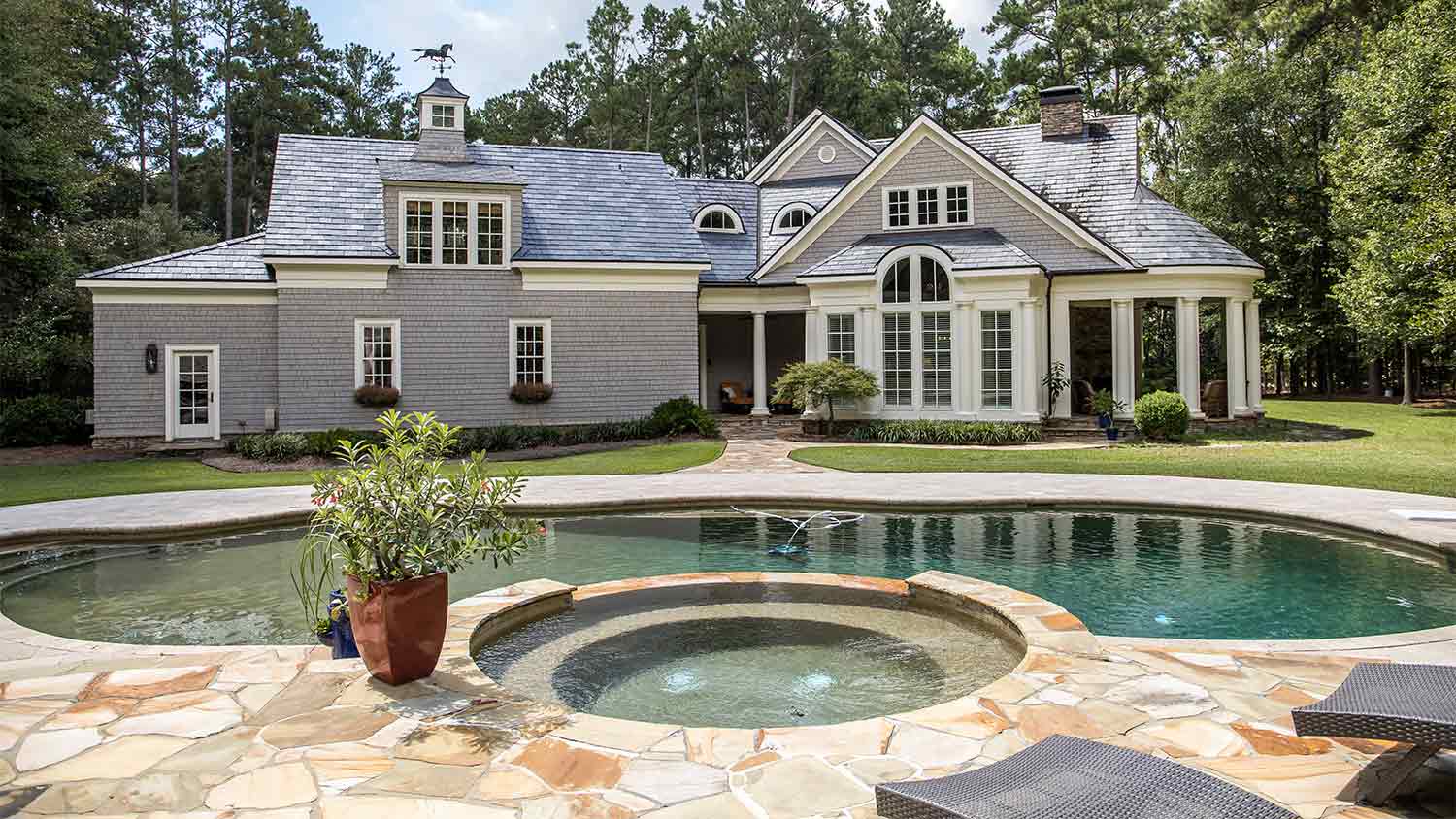 A view of an in-ground hot tub and swimming pool in a backyard