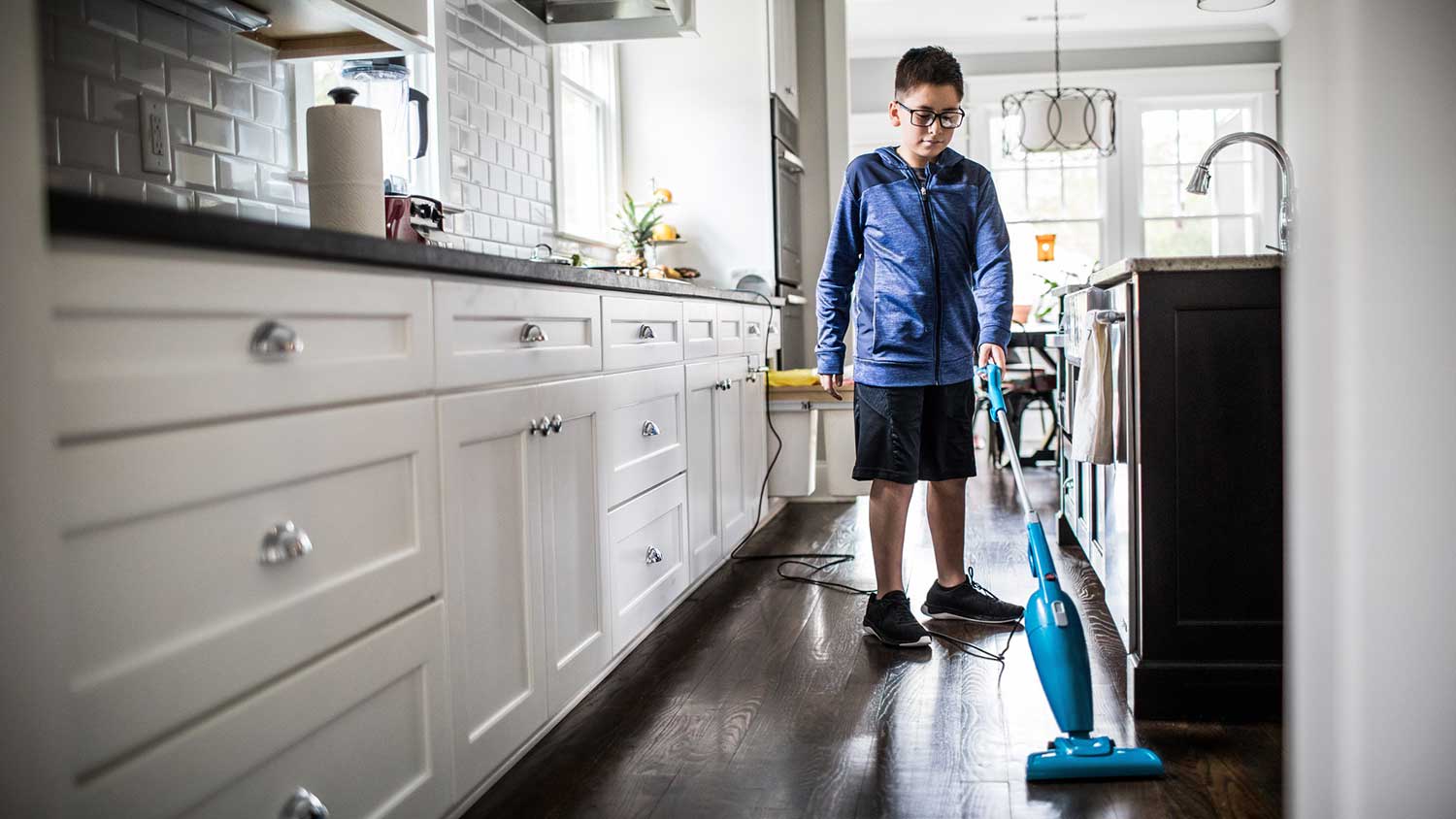 Boy vacuuming kitchen floor