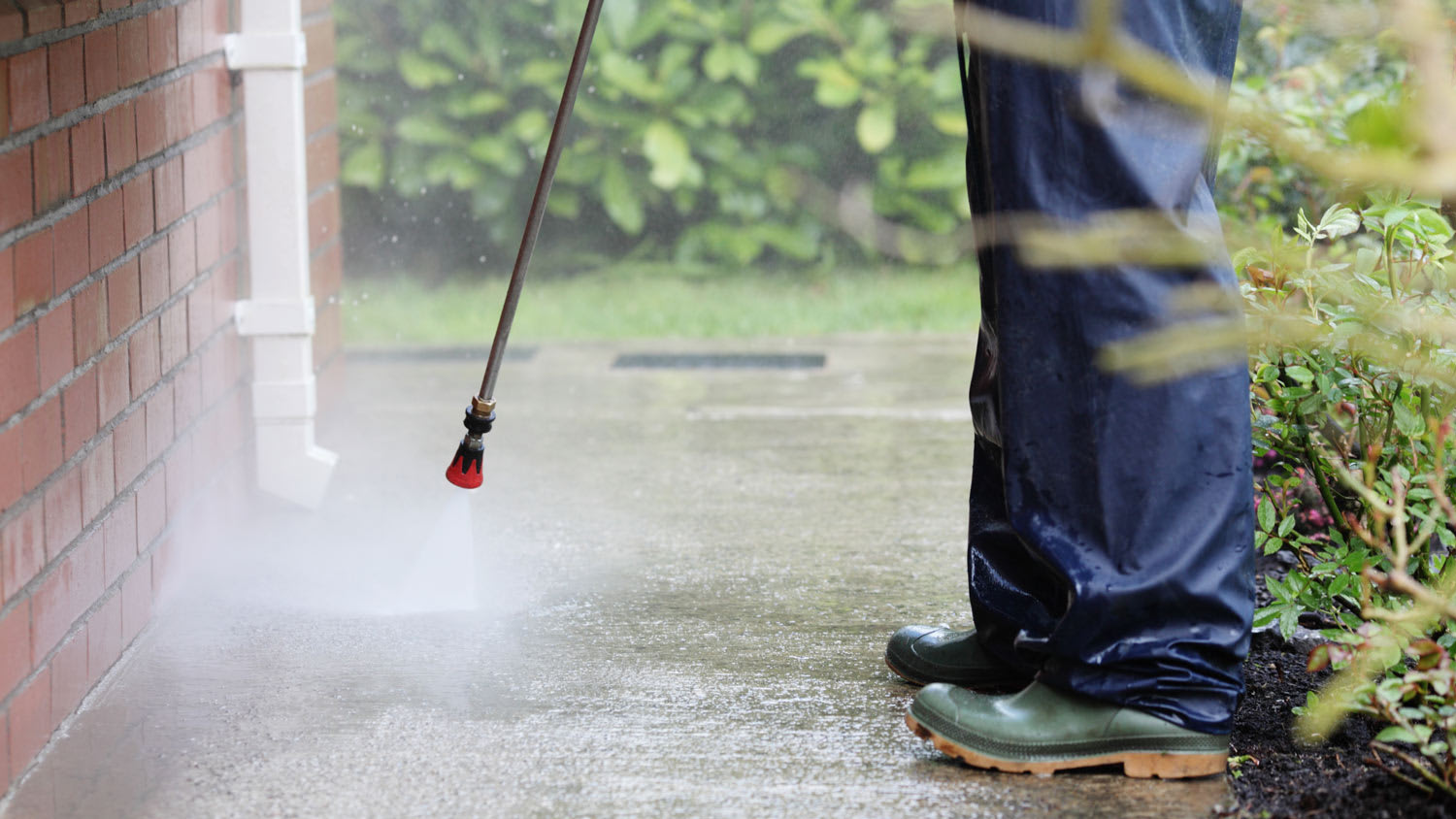 Detail of a person cleaning pathway using a pressure washer