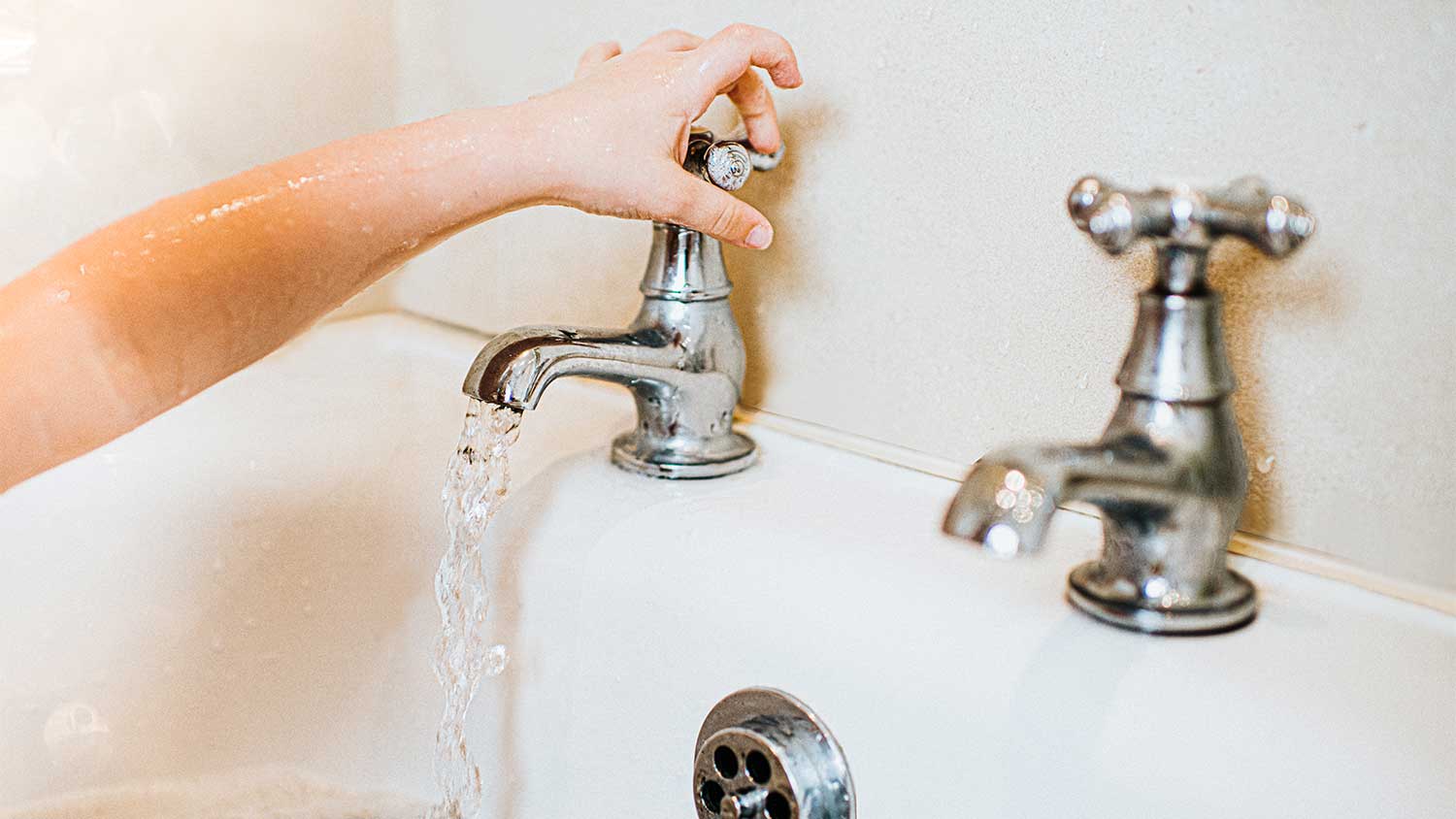 A view of someone turning off the water in a bathtub