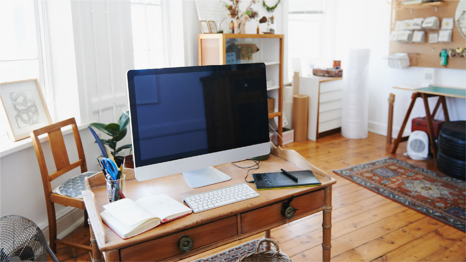 wooden desk with monitor in middle of artist studio
