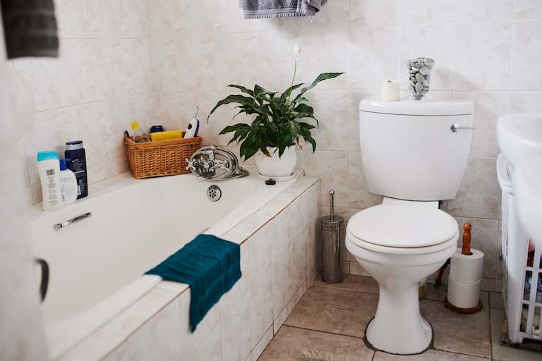 home bathroom with toilet, tile floors and objects placed around bathtub shower combo