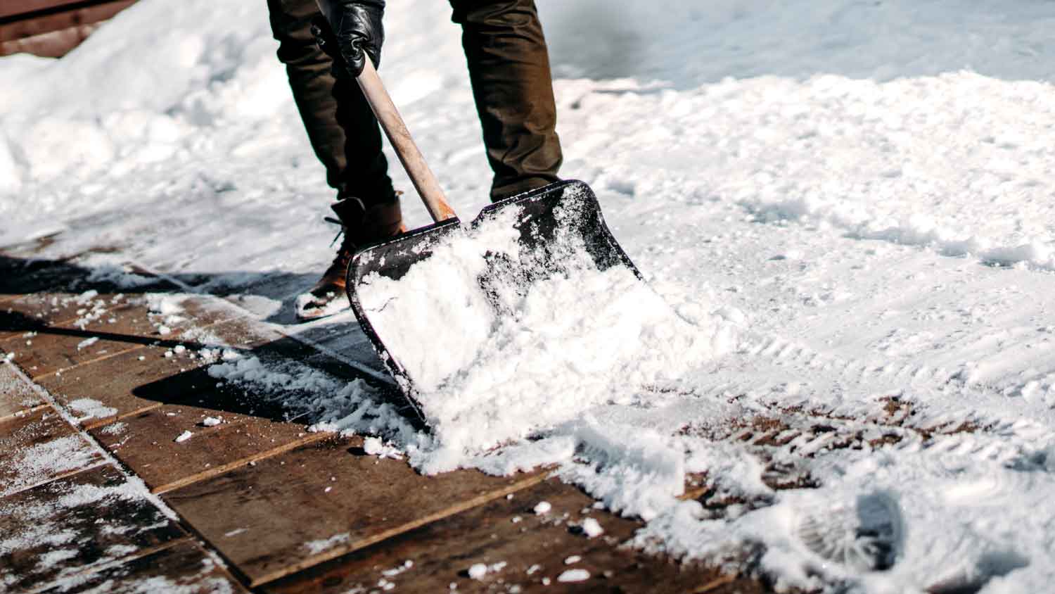 A man shovelling snow in his house’s driveway