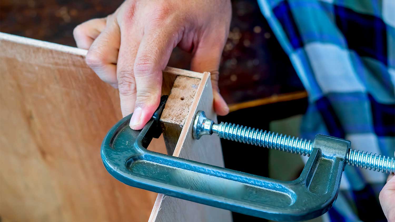 A view of someone using a clamp on a wood project