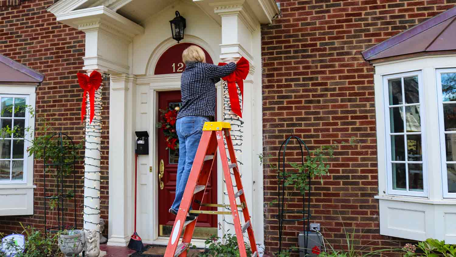 woman adding bows to columns outside home