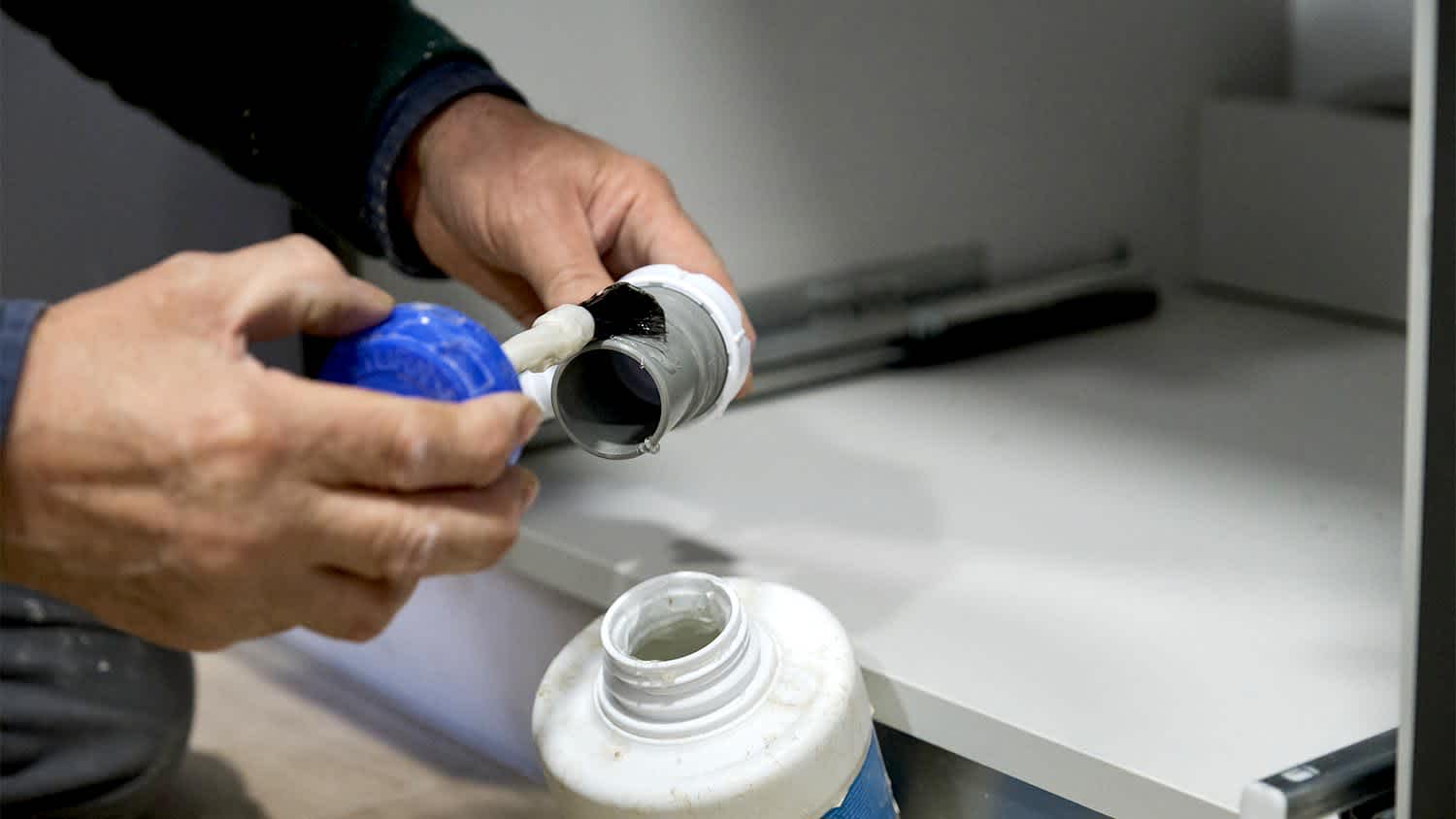 A man uses PVC glue on piping