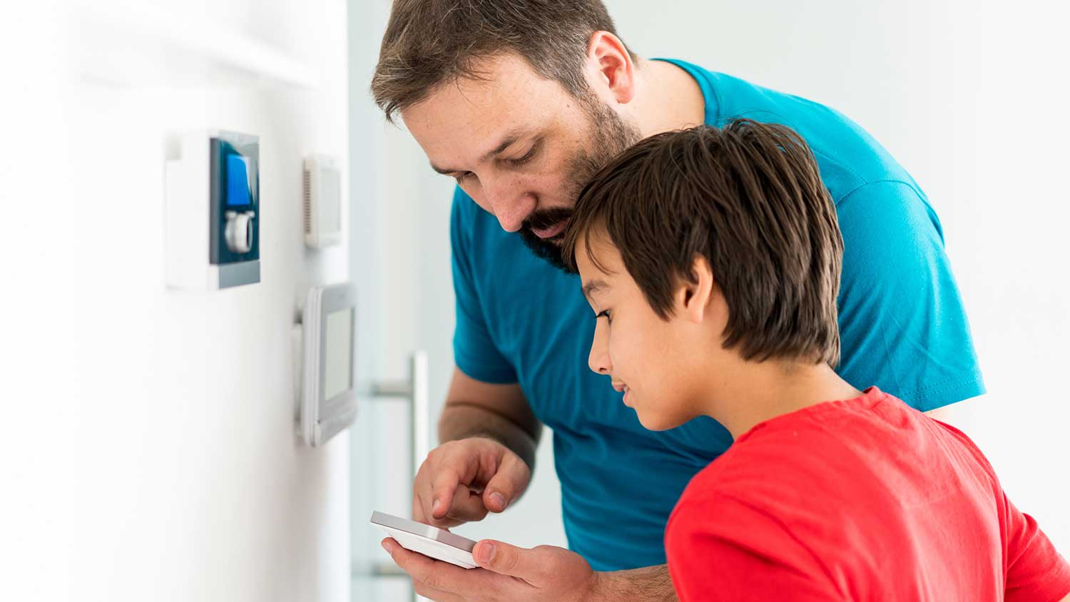 Father and son using smart phone to set up thermostat