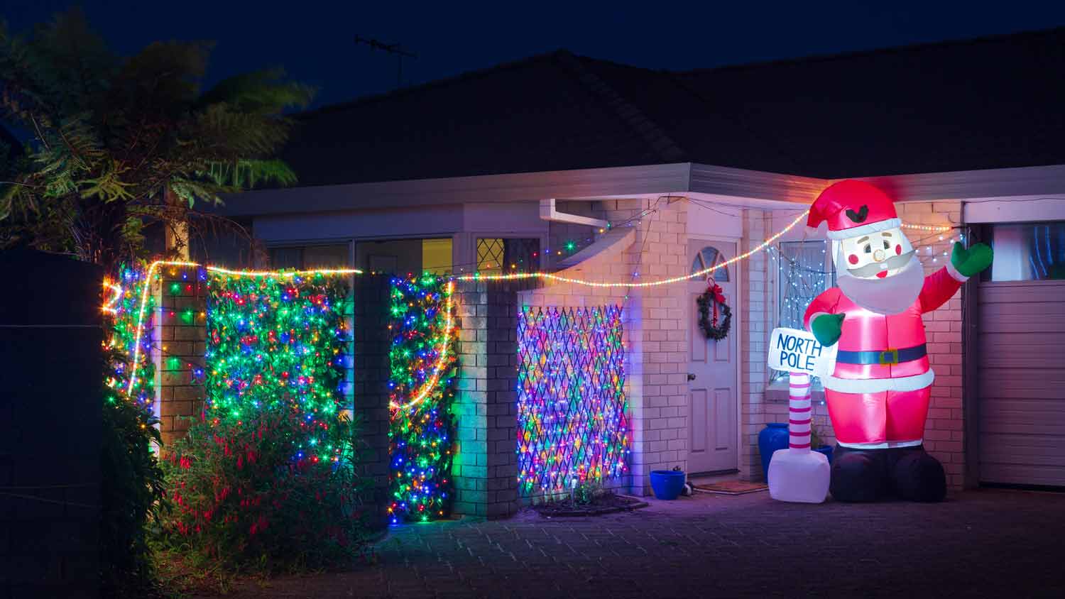 An inflatable illuminated Santa Claus outside a house